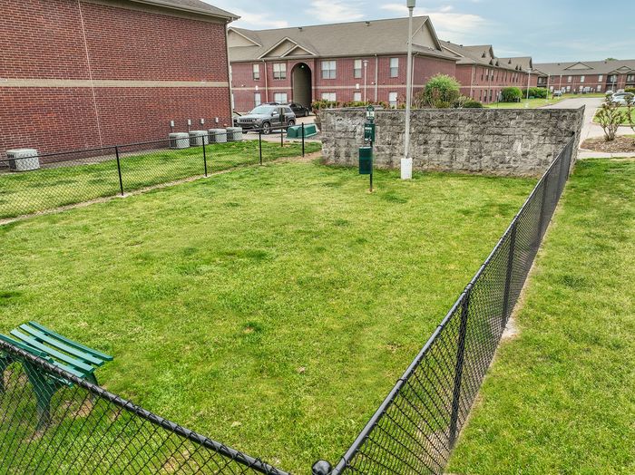 Charming apartment complex with a lush green fenced common area, perfect for relaxation and outdoor activities.