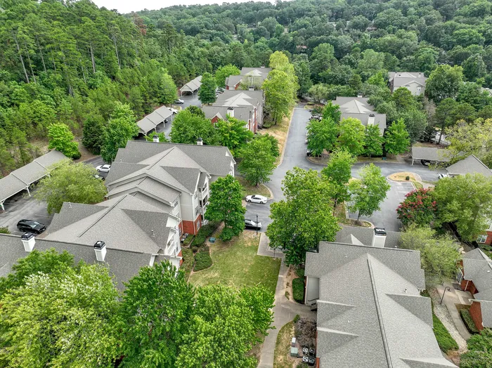 Charming aerial view of a serene apartment community nestled among lush greenery with spacious parking and inviting pathways.