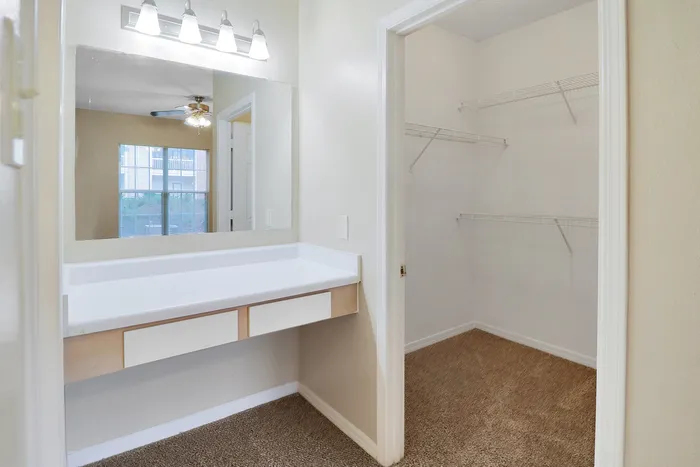 Bright and inviting dressing area with a large mirror and open walk-in closet, offering ample storage space.
