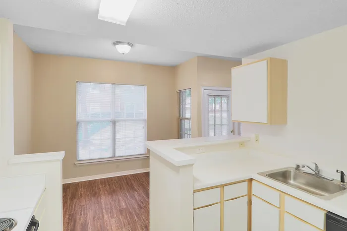 Bright and inviting open-plan living space with hardwood floors, ample natural light, and a modern kitchen with sleek countertops.