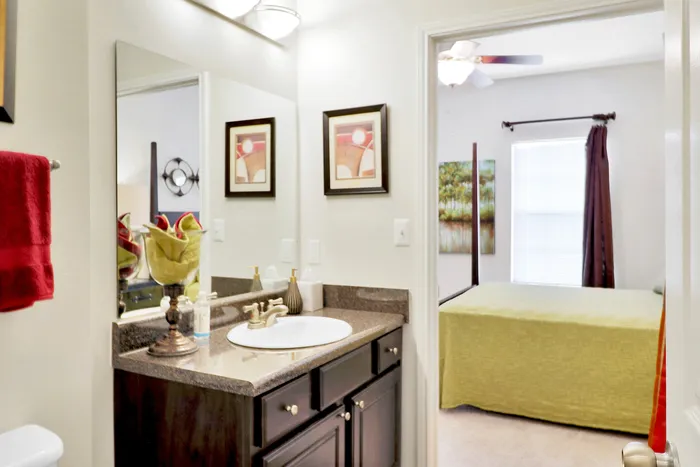 Elegant bathroom with granite countertop and art accentuated by a view into a cozy, well-lit bedroom.