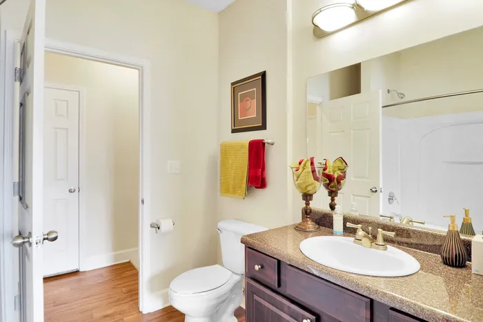Elegant bathroom featuring a sleek granite countertop, stylish fixtures, and tasteful decor with framed art and plush towels.