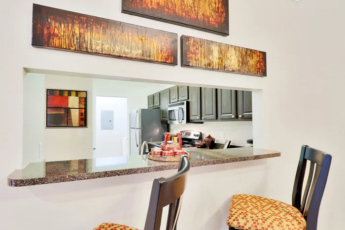 Chic kitchen nook with stylish bar stools, modern appliances, and vibrant artwork, offering a cozy dining experience.
