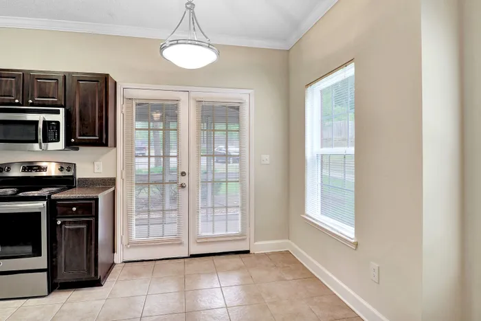 Bright kitchen with modern appliances, elegant cabinetry, and French doors leading to a serene outdoor view.