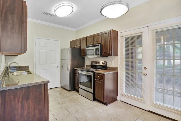 Elegant kitchen with stainless steel appliances, rich wooden cabinets, and large French doors for natural light.