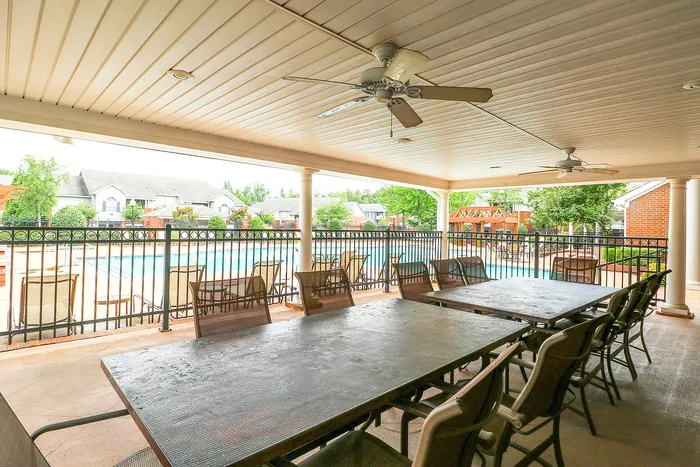 Charming covered patio overlooking a sparkling pool, featuring elegant seating and ceiling fans for comfortable outdoor gatherings.