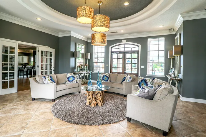 Elegant living room with modern gray walls, plush sofas, artistic decor, and a unique wooden centerpiece under ambient lighting.