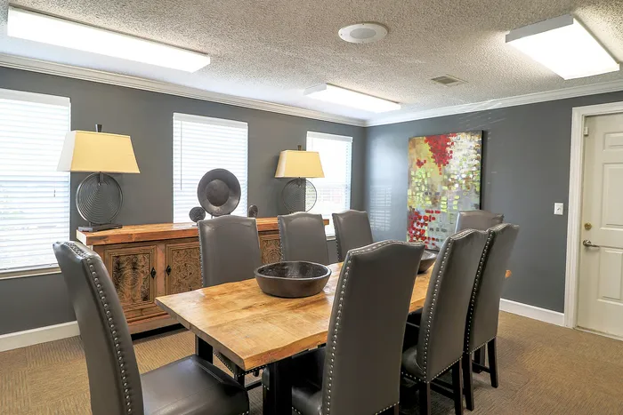 Elegant dining room with modern gray chairs and a rustic wooden table, complemented by chic decor and vibrant artwork, ideal for stylish gatherings.