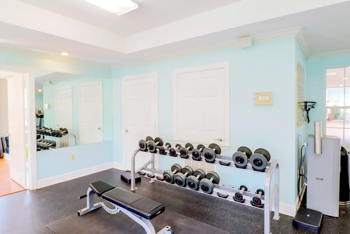 Bright and inviting fitness room with modern dumbbell rack and comfortable exercise bench.