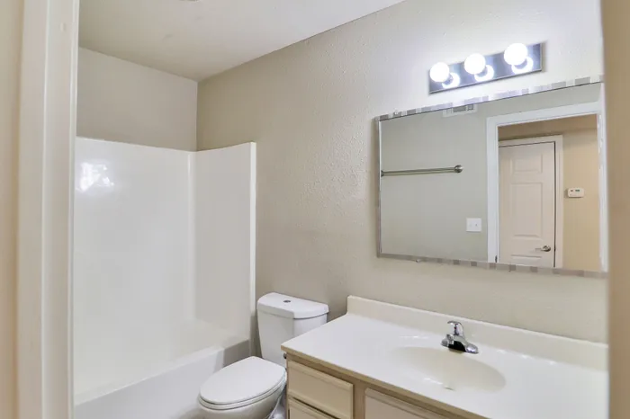 Bright and modern bathroom with sleek white fixtures, spacious vanity, and elegant lighting.