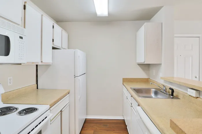 Bright kitchen with sleek white cabinetry, modern appliances, and warm wood flooring for a welcoming ambiance.