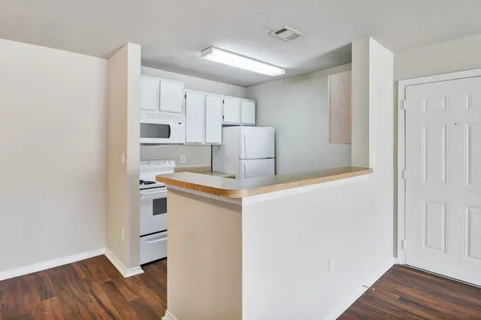 Charming kitchen with modern appliances and sleek cabinetry, complemented by stylish wood flooring.