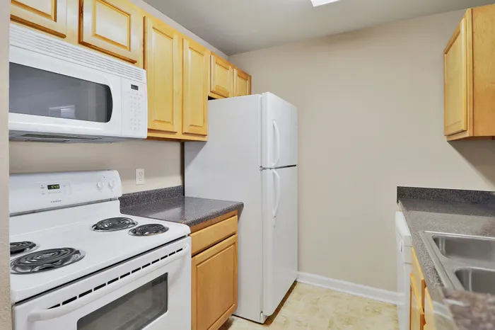 Compact, efficient kitchen with modern appliances, light wood cabinets, and sleek countertops for a charming culinary experience.