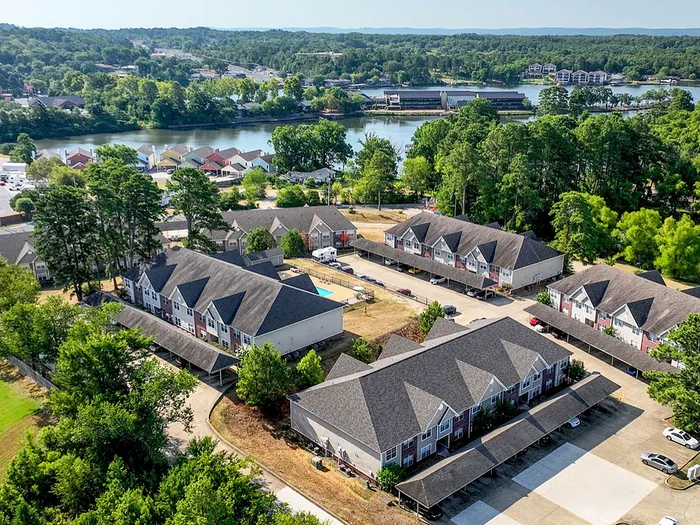 Aerial view of a serene apartment community surrounded by lush greenery, offering stunning lake views and modern amenities.