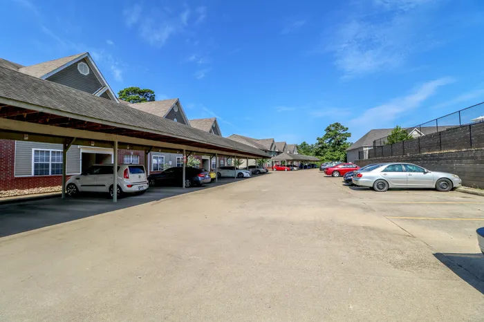 Charming residential complex with covered parking, showcasing stylish architecture under a bright blue sky.