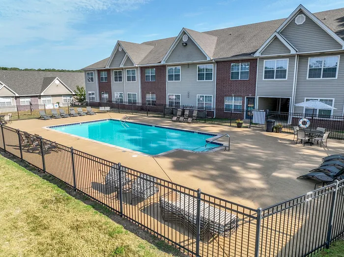 Inviting apartment community with a sparkling outdoor pool, surrounded by comfortable lounge chairs and stylish brick and siding architecture.