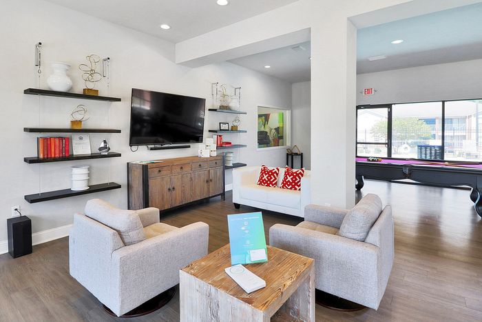 Inviting living space featuring modern furniture, a large flat-screen TV, and stylish decor, complemented by a pool table and abundant natural light.