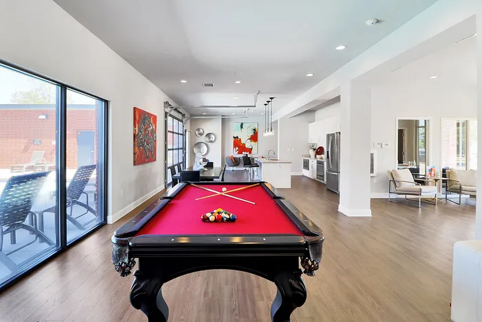 Luxurious open-concept apartment featuring a stylish billiard table, modern kitchen with stainless steel appliances, and elegant living area with contemporary art.