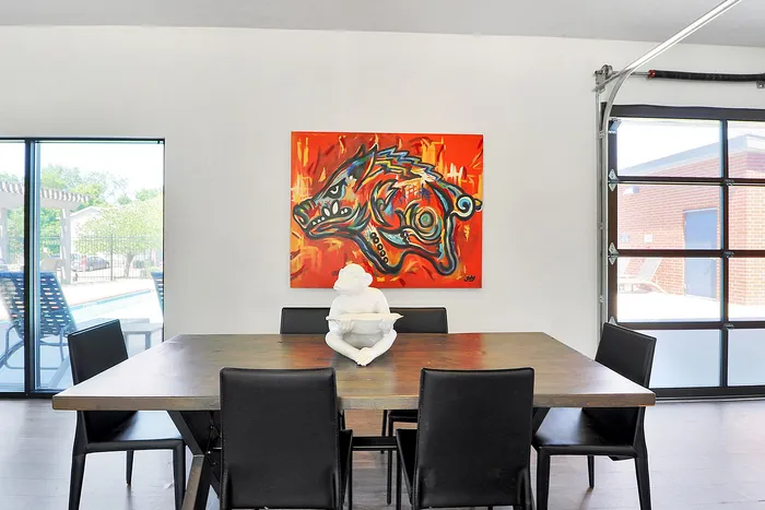 Modern dining room with vibrant abstract art, elegant table setting, and large windows for natural light.