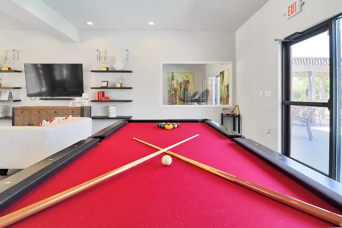 Inviting entertainment room showcasing a vibrant red pool table, modern decor, and large wall-mounted TV.