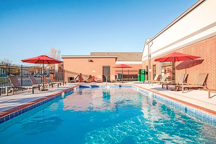 Inviting outdoor pool area with sun loungers and red umbrellas, perfect for relaxation and leisure.