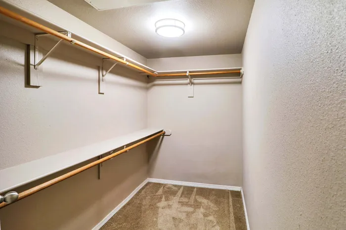 Spacious walk-in closet with elegant lighting and ample shelving for organized storage.
