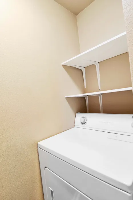 Compact laundry nook featuring a modern white washing machine with built-in shelving for efficient storage.