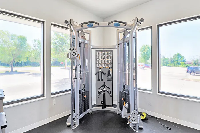 Bright fitness center featuring a state-of-the-art cable machine with panoramic windows offering a vibrant outdoor view.