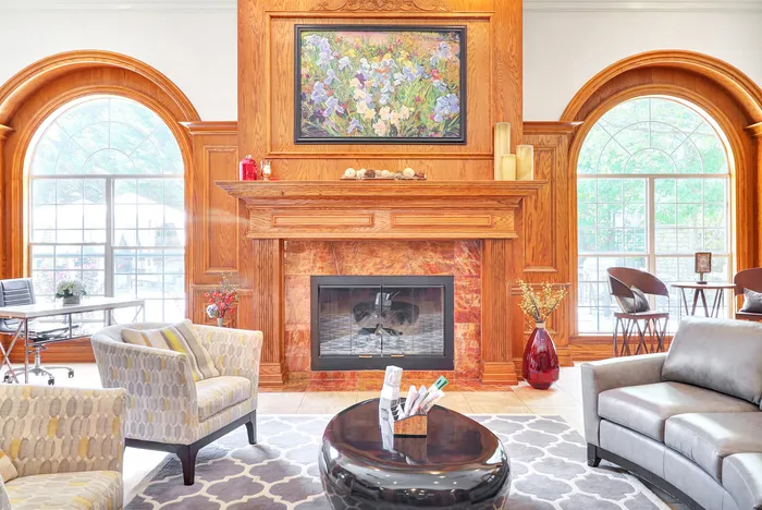 Elegant living room showcasing a cozy fireplace with exquisite wood paneling, stylish seating, and large arched windows for natural light.