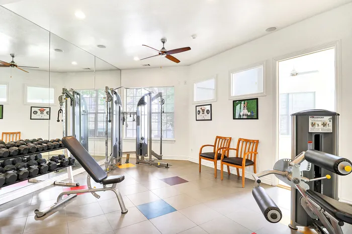 Bright and modern fitness center with state-of-the-art equipment and mirrored walls, offering a spacious and inviting environment for workouts.