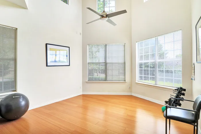 Bright and airy living space with high ceilings, abundant natural light from large windows, and elegant wooden flooring, perfect for a home gym or creative area.