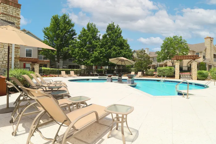 Inviting outdoor pool area with elegant lounge chairs, umbrellas, and lush greenery, perfect for relaxation and leisure.
