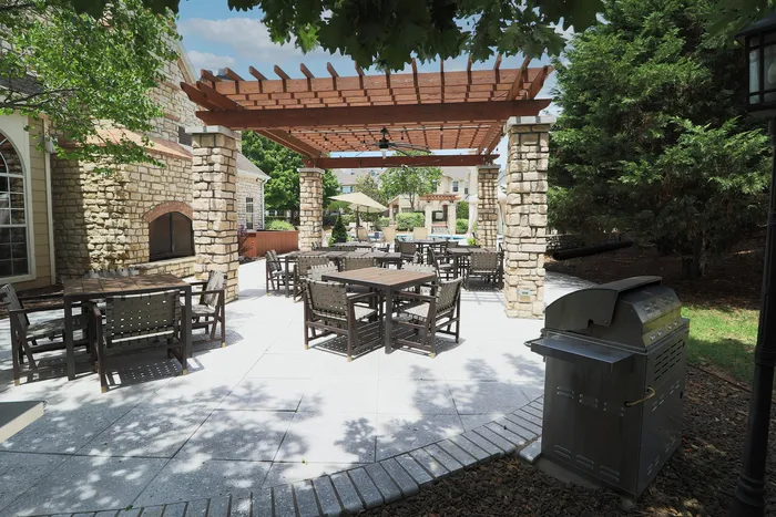 Charming outdoor patio with stylish wood pergola, stone accents, and modern dining furniture, ideal for al fresco gatherings.