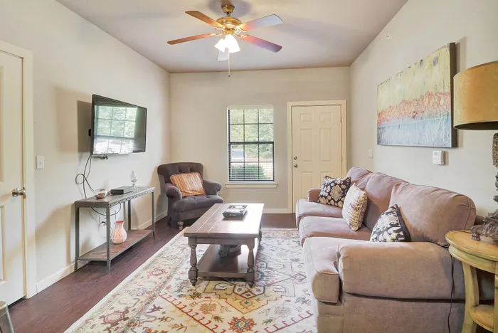 Inviting living room with cozy sofas, a vibrant area rug, wall-mounted TV, and tasteful decor, offering a perfect blend of comfort and style.