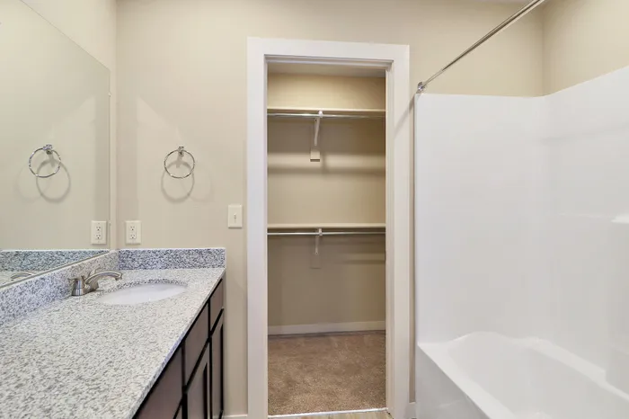 Modern bathroom with sleek granite countertop, elegant fixtures, and spacious walk-in closet offering ample storage.