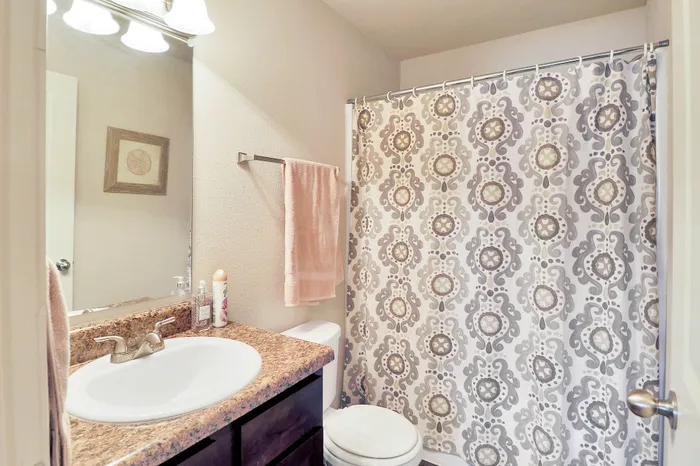Charming bathroom showcasing a stylish patterned shower curtain, elegant sink with marble countertop, and soft ambient lighting.