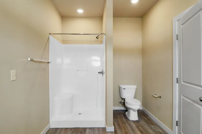Bright and modern bathroom featuring a sleek walk-in shower and elegant wood flooring.