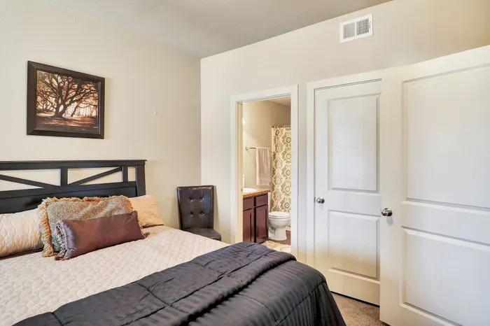 Inviting bedroom with cozy bedding and en-suite bathroom, enhanced by warm decor and elegant furnishings.