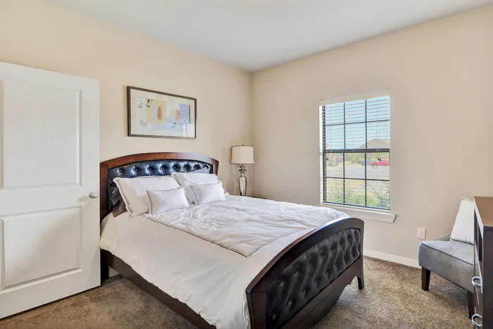Inviting bedroom featuring a luxurious bed with plush bedding, a stylish bedside lamp, and natural light streaming through the window.