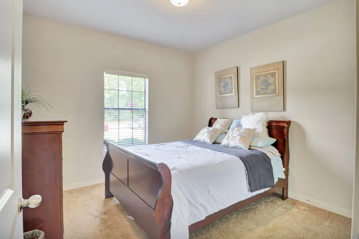 Inviting bedroom with elegant wooden furniture, plush bedding, and natural light streaming through a large window.
