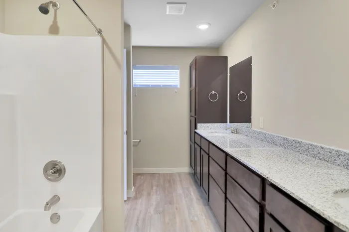 Bright modern bathroom with elegant granite countertops and dual sink vanity, showcasing luxurious bath fixtures and ample storage.