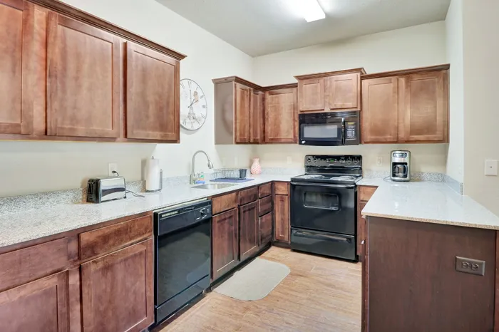 Elegant kitchen with dark wood cabinets, modern black appliances, and sleek granite countertops.