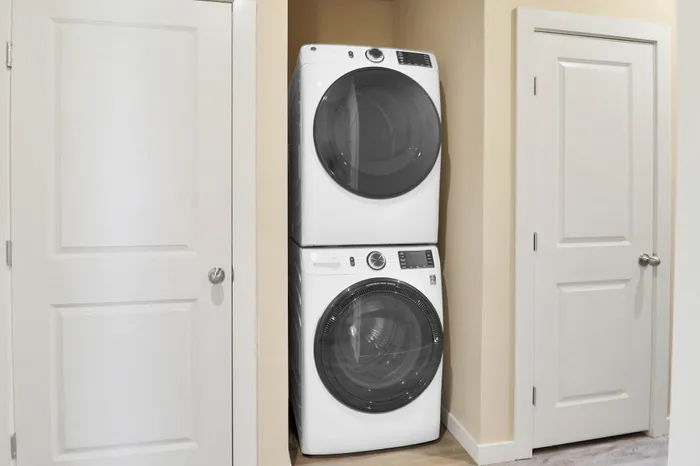 Modern laundry nook featuring a sleek, stacked washer and dryer in a compact, stylish space.