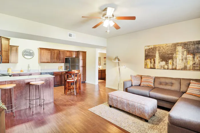 Inviting open-concept living space with stylish kitchen, plush gray sofa, modern artwork, and warm wooden floors.