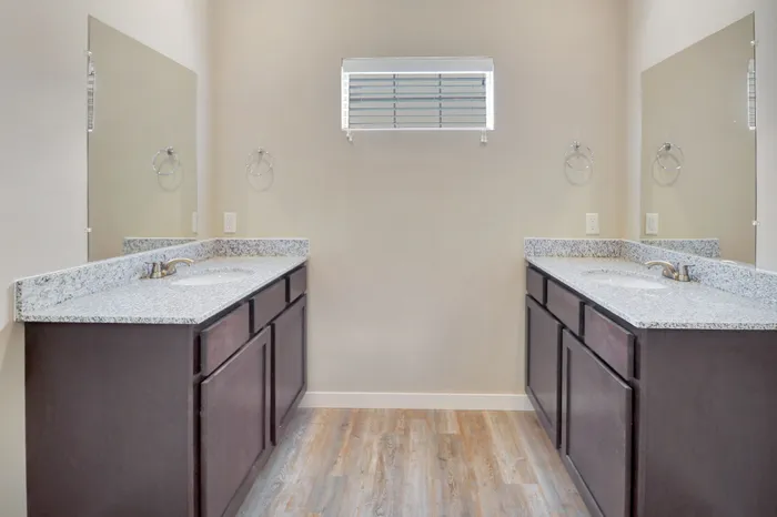 Elegant dual-sink bathroom with granite countertops and contemporary cabinetry, offering a luxurious and functional space.