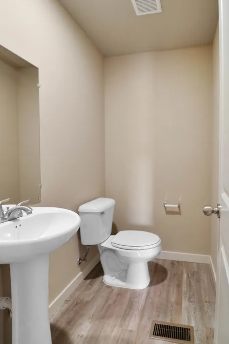 Sleek contemporary bathroom with modern pedestal sink and elegant wooden flooring.
