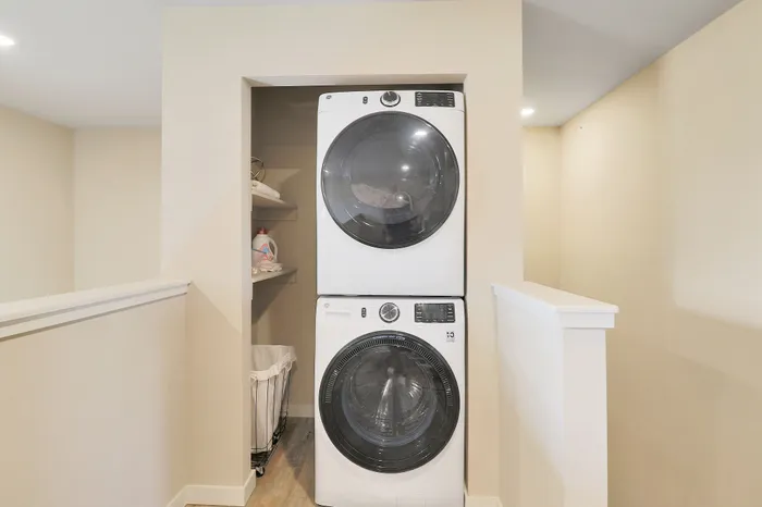Modern laundry closet featuring a sleek stackable washer and dryer with convenient shelving for storage.