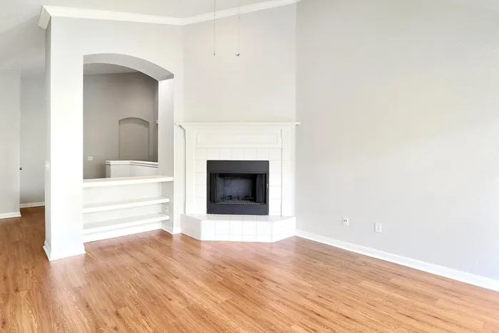 Bright and inviting living room with elegant fireplace, showcasing beautiful wood flooring and a stylish open shelving nook.