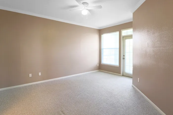 Bright and inviting room with large windows, beige walls, and plush carpeting, perfect for a cozy and stylish living space.