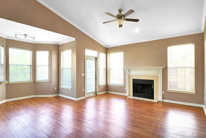 Bright living room with natural light, elegant fireplace, and gleaming hardwood floors.